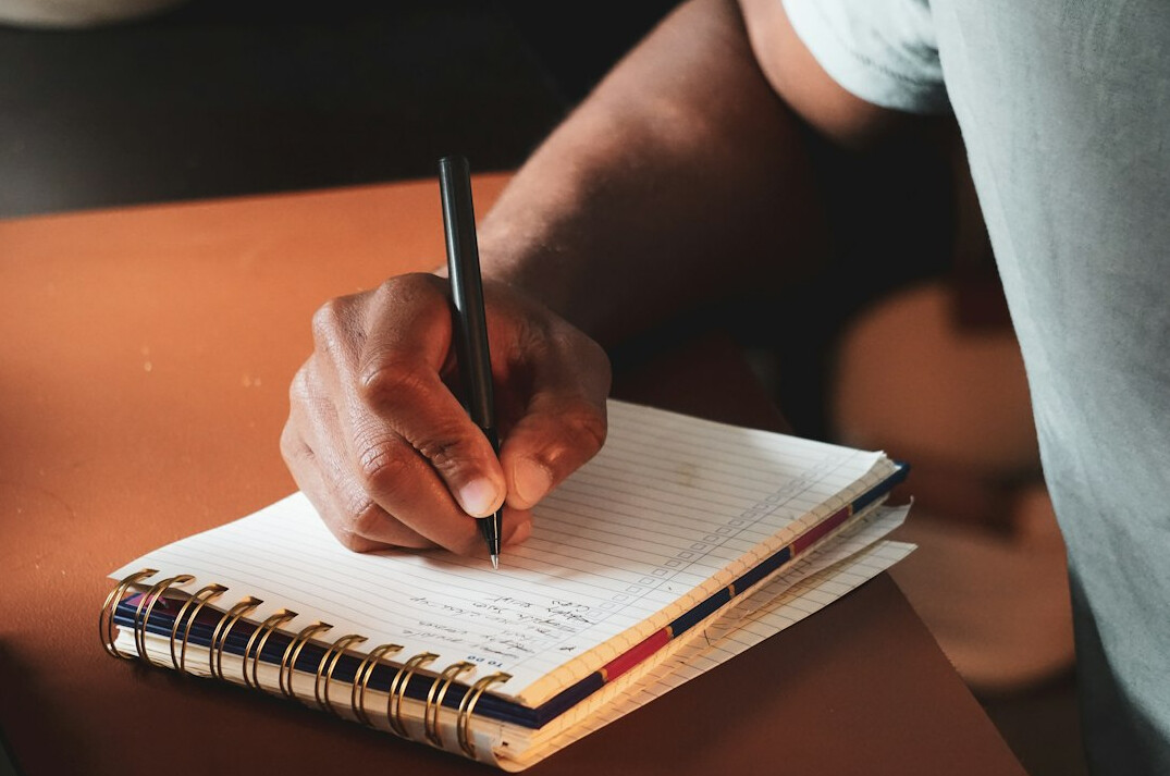 person writing notes in notebook